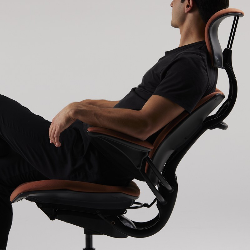 Person reclining in a Humanscale Freedom chair as the headrest and armrests move with them